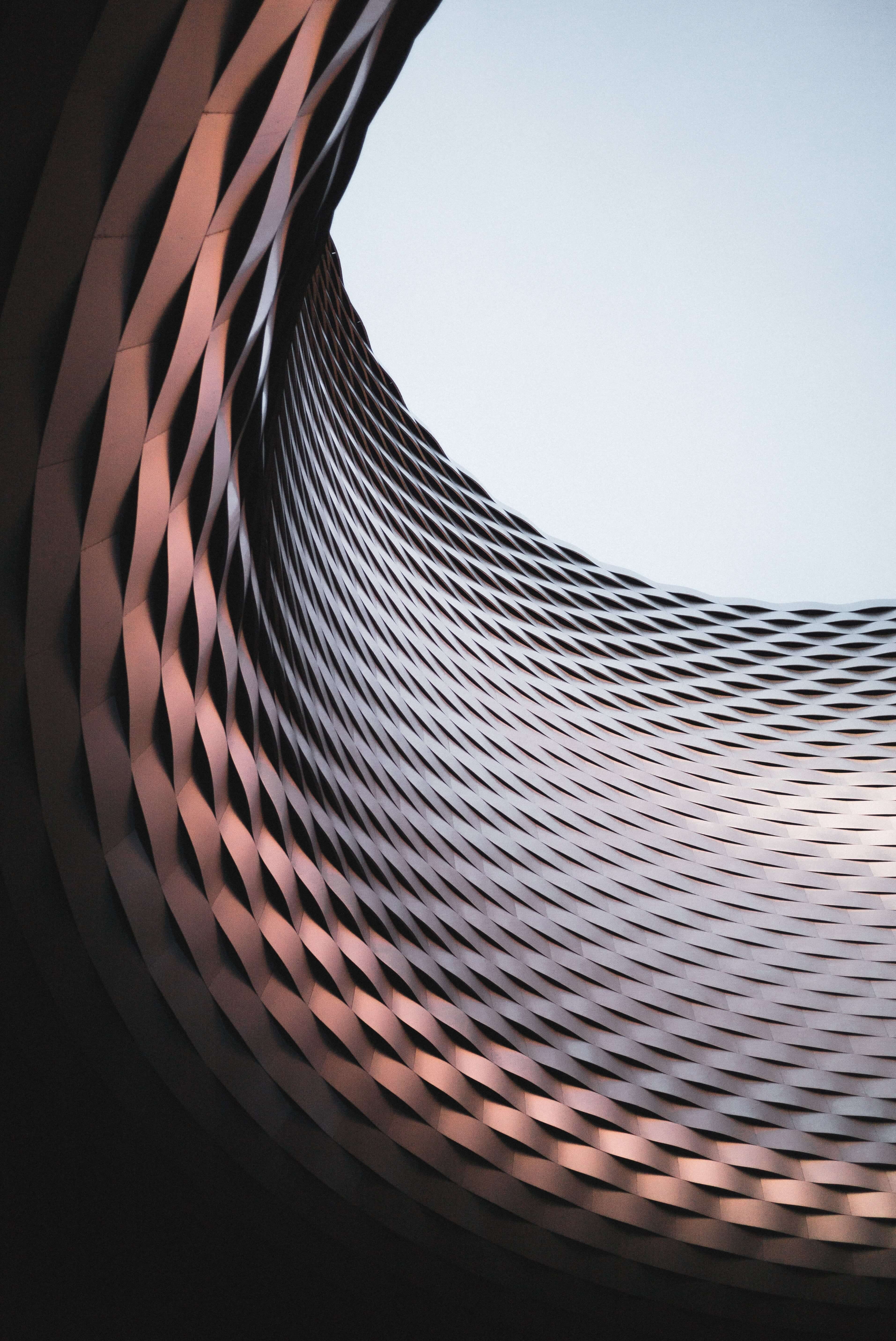 Architectural detail with copper tones and a wave-like pattern against the sky, symbolic of Caldera Capital's fluid and adaptable strategies in corporate finance and M&A advisory.