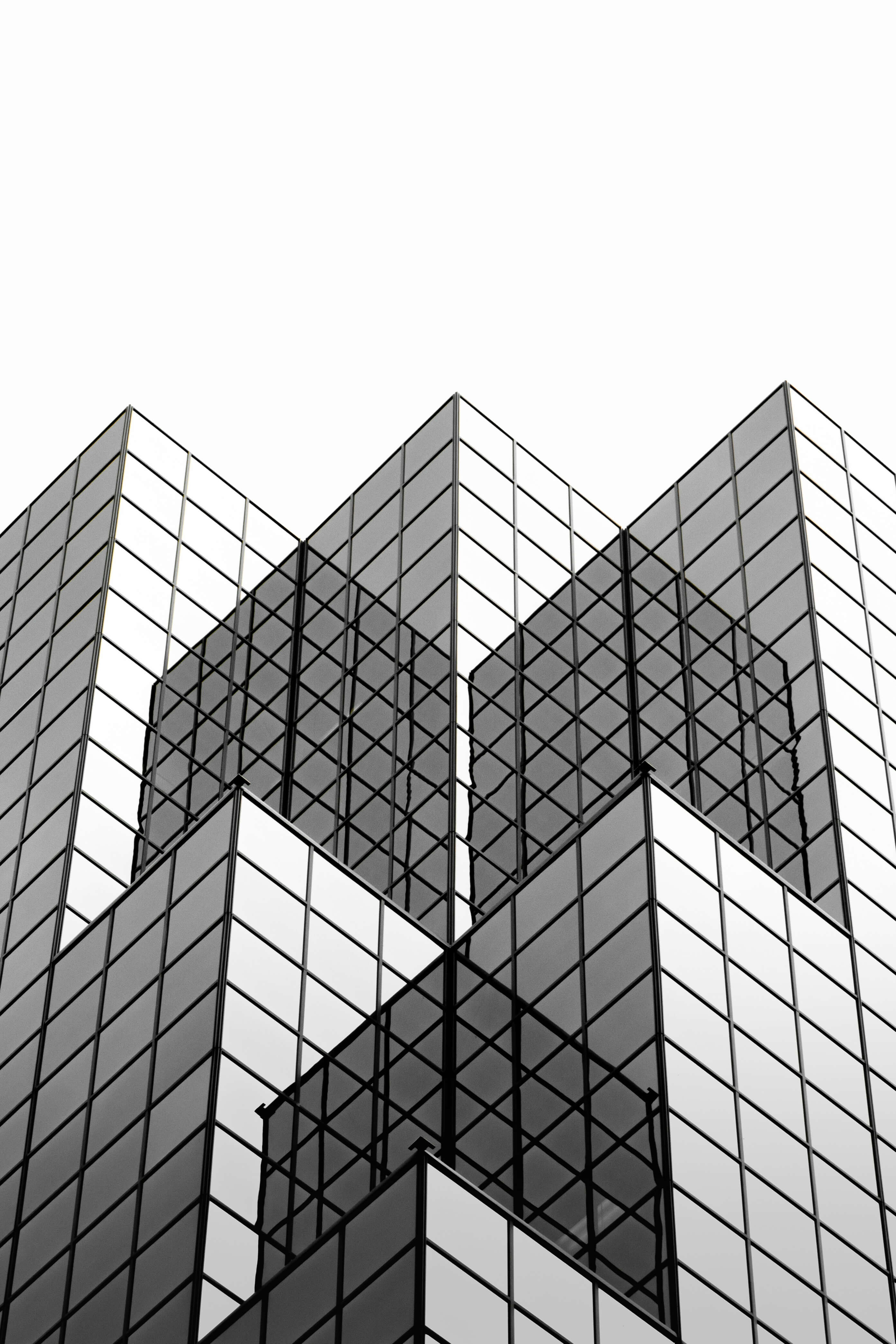 Reflective glass building with geometric design, representing the transparency and precision in Caldera Capital’s financial services.