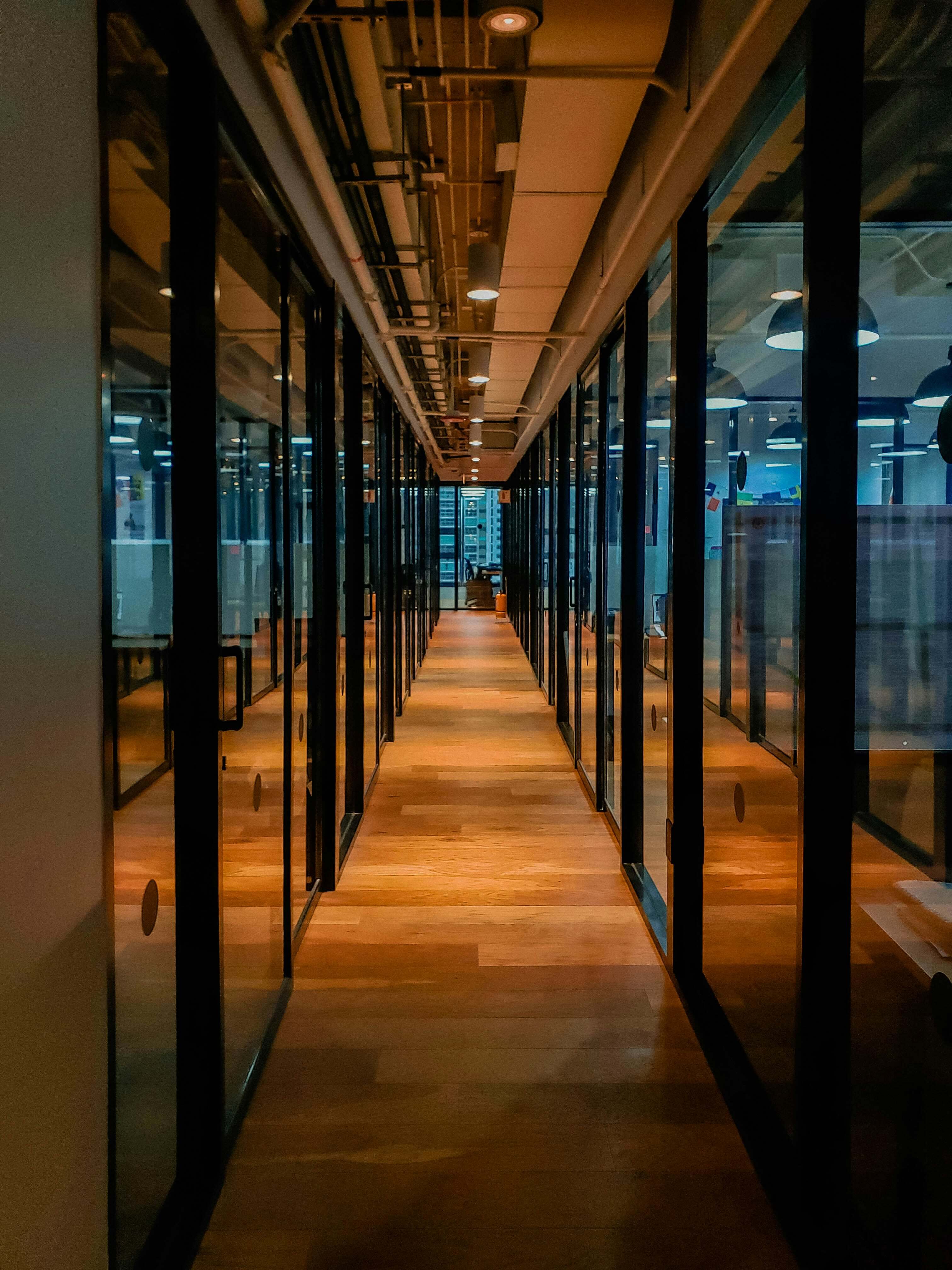 A corridor lined with reflective glass doors, echoing Caldera Capital’s transparent and direct approach to client engagements in investment banking and corporate advisory